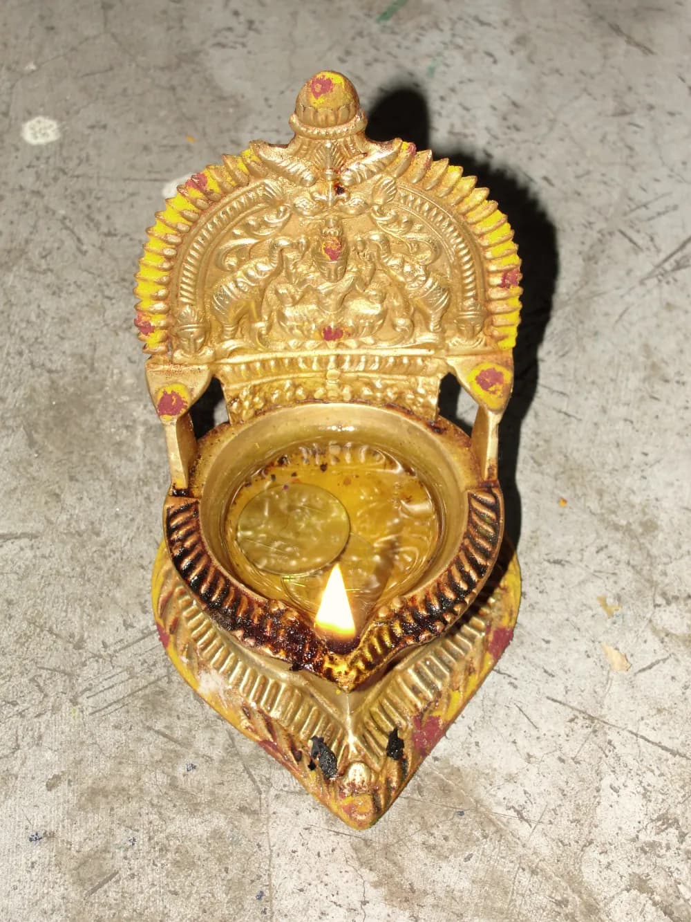 A brass deepam with a single lit wick