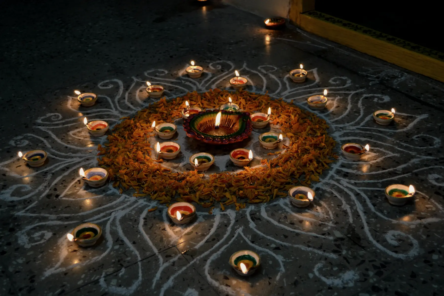 A rangoli of marigold petals ringed with lit diyas