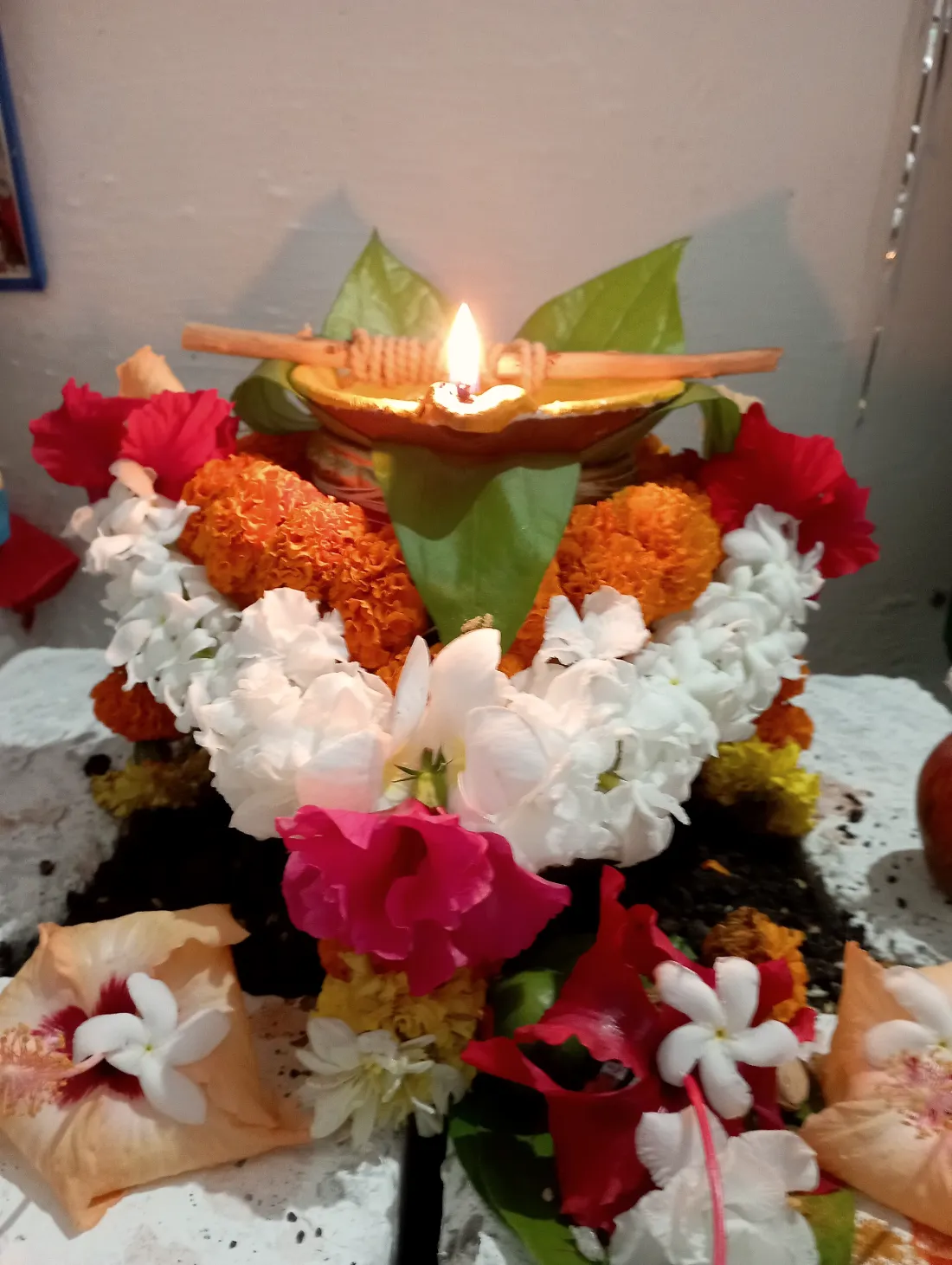 A kalash with a lit diya, garlanded with marigold and jasmine