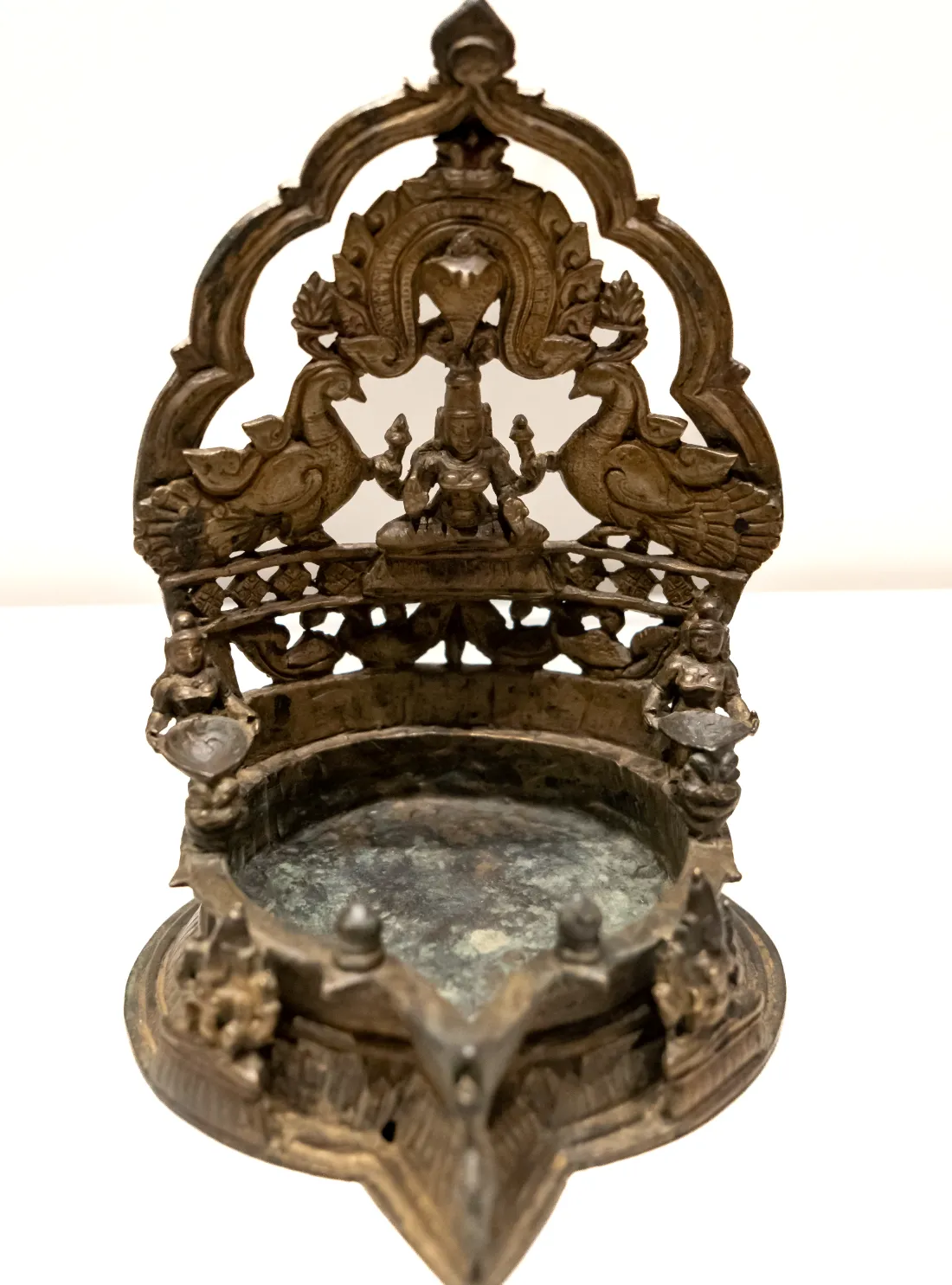 A brass lamp crowned with a figure of Lakshmi