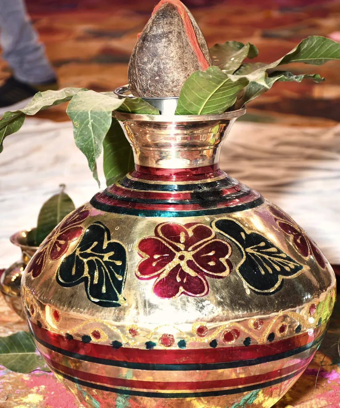 A painted brass kalash with mango leaves, prepared for a wedding