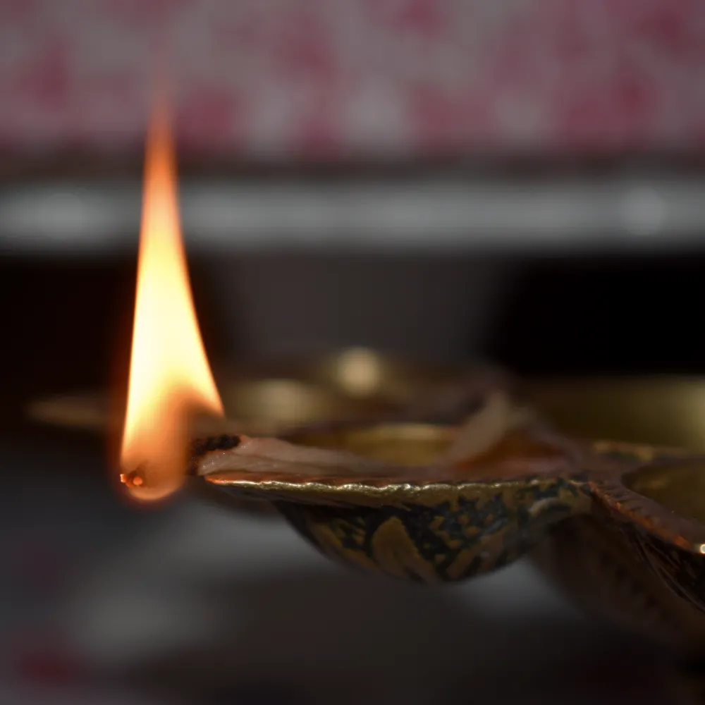 A single oil lamp flame beside a brass diya