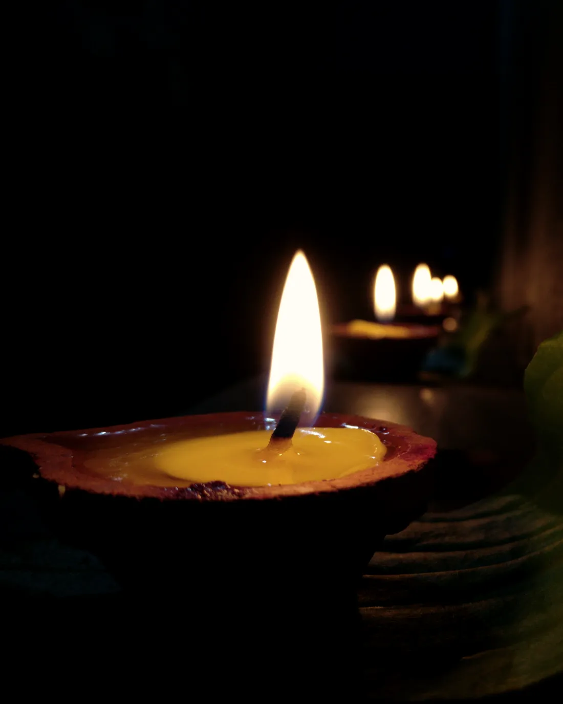 A clay diya burning in a darkened room